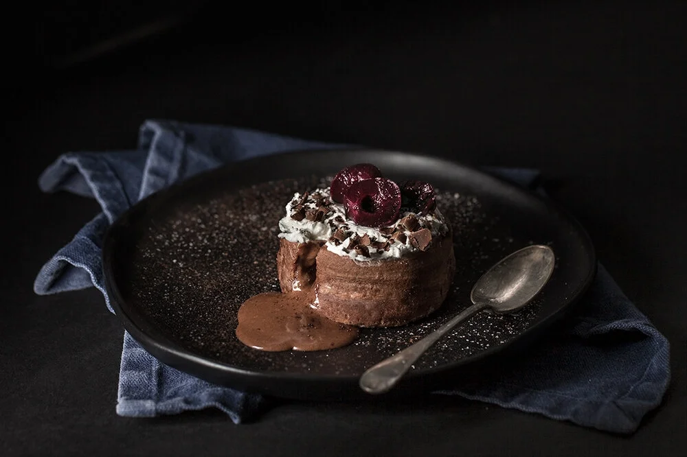 Molten chocolate lava cake with cherries and whipped cream.